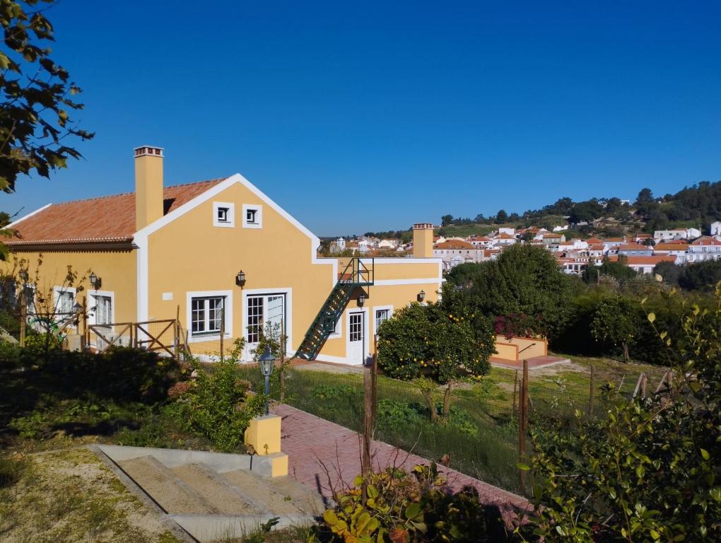 uma casa amarela com uma cidade ao fundo em Villa Rosa - Quinta do Santo Espírito em Aveiras de Baixo