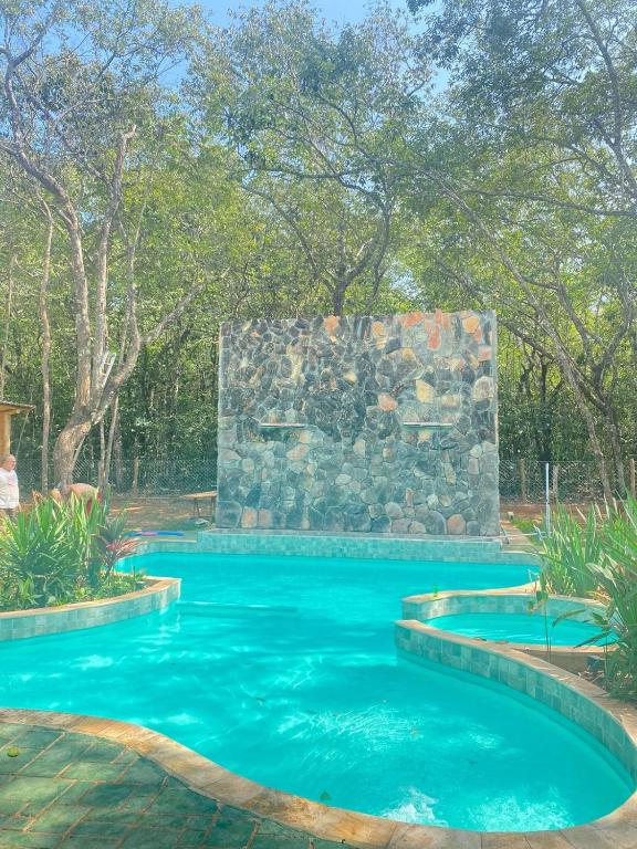 a pool with a stone wall and blue water at Sítio Quinta da mata - Casa Amarela in Pirenópolis
