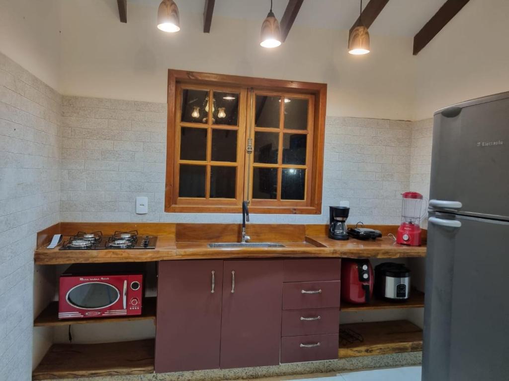 uma cozinha com um balcão com um lavatório e um frigorífico em Sítio Quinta da Mata Chalé Amarelo em Pirenópolis