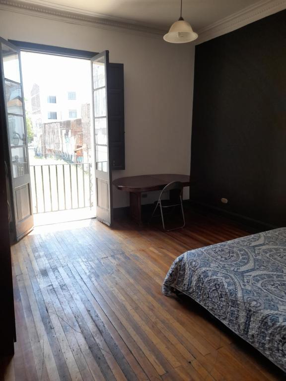 um quarto com uma cama, uma mesa e uma janela em Student's Housing Republica em Santiago