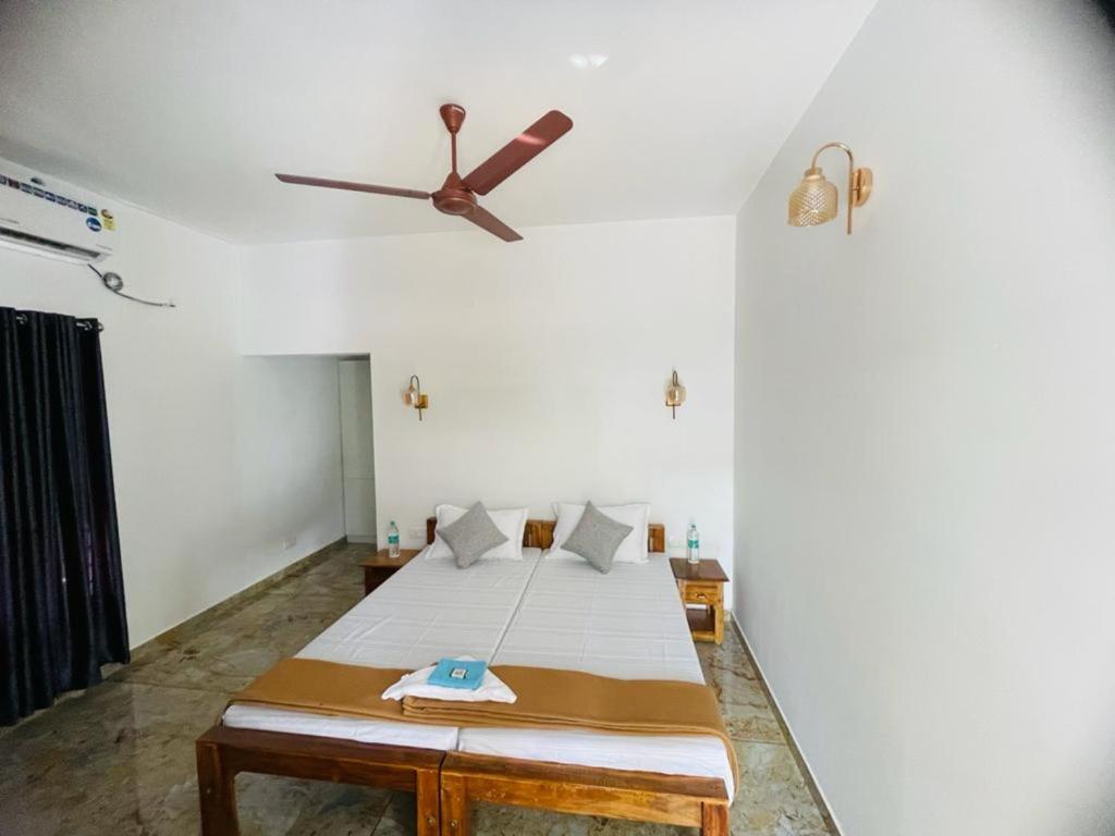 Habitación con cama y ventilador de techo. en SALT LIFE MARARI BEACH VILLA, en Mararikulam