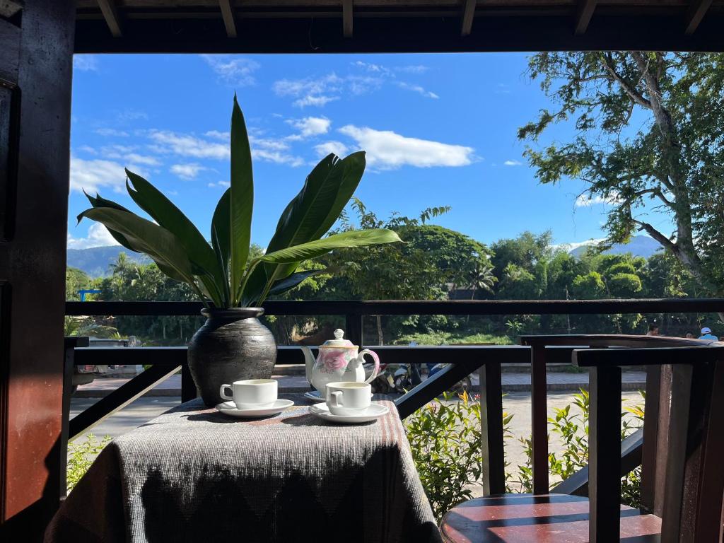 a table with a vase and two cups of coffee at Villa Namkhan Heritage in Luang Prabang