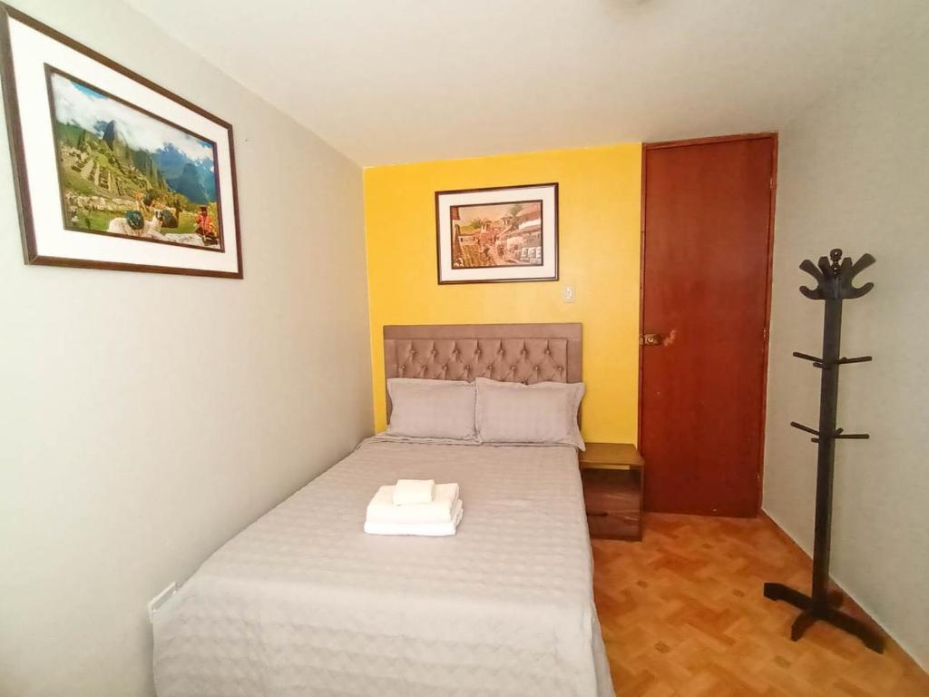 un pequeño dormitorio con una cama con una cruz. en Confortable habitación doble frente al Aeropuerto, en Lima