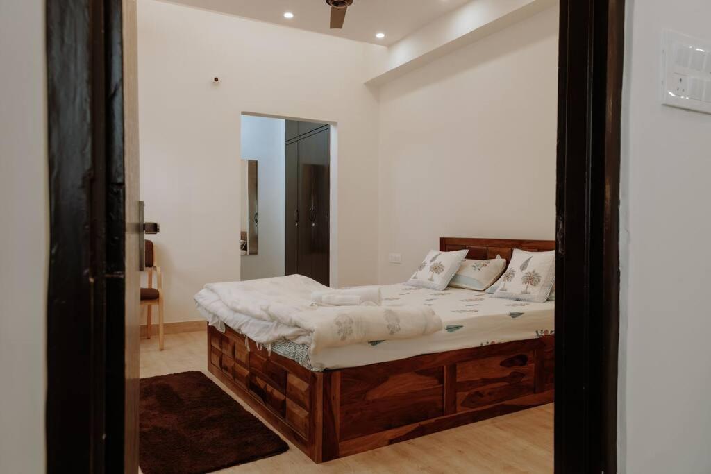 1 dormitorio con cama de madera y espejo en Casa Paradis- secure, cozy& peaceful paradise in heart of most happening colony, en Jaipur