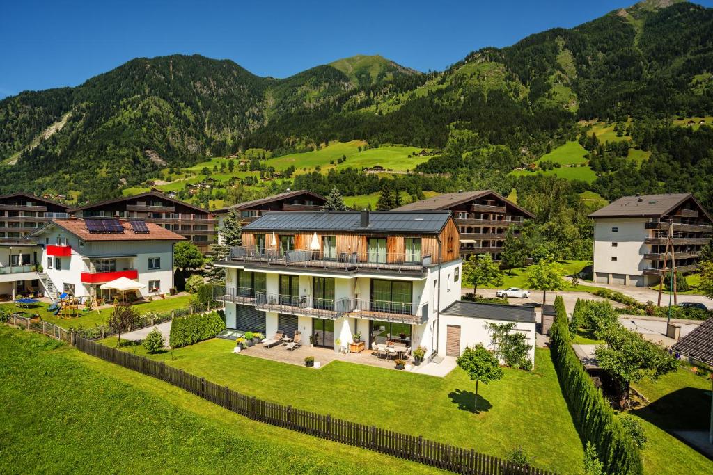 a large house on a hill with mountains in the background at Fuchs Apartments - inklusive Eintritt in die Alpentherme Gastein in Bad Hofgastein