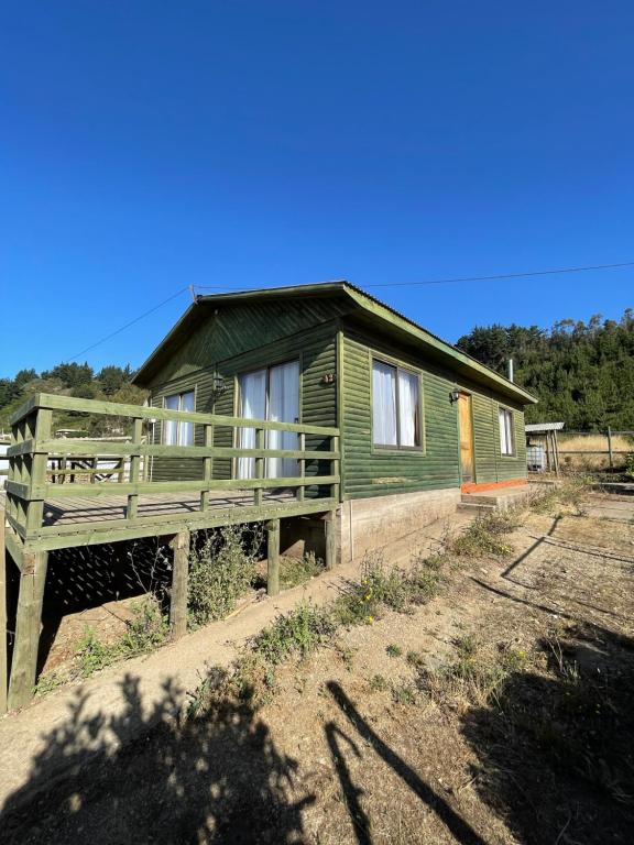 uma pequena casa verde com um alpendre num campo em Cabaña en pelluhue 5 personas em Pelluhue