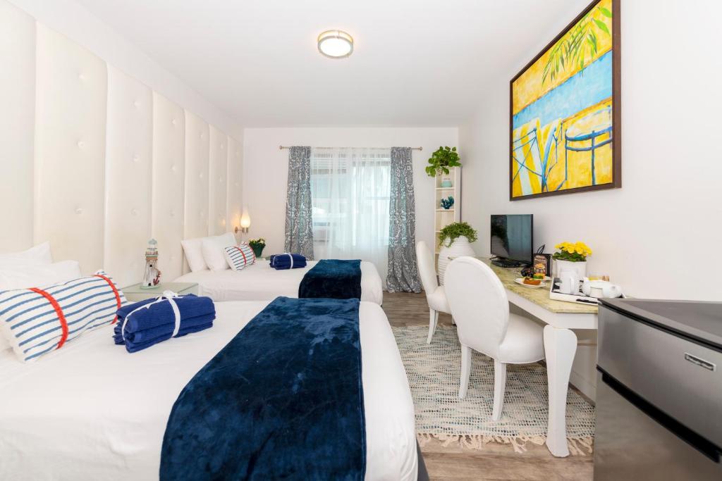 a hotel room with two beds and a desk at 6768 Collins Miami Stays in Miami Beach