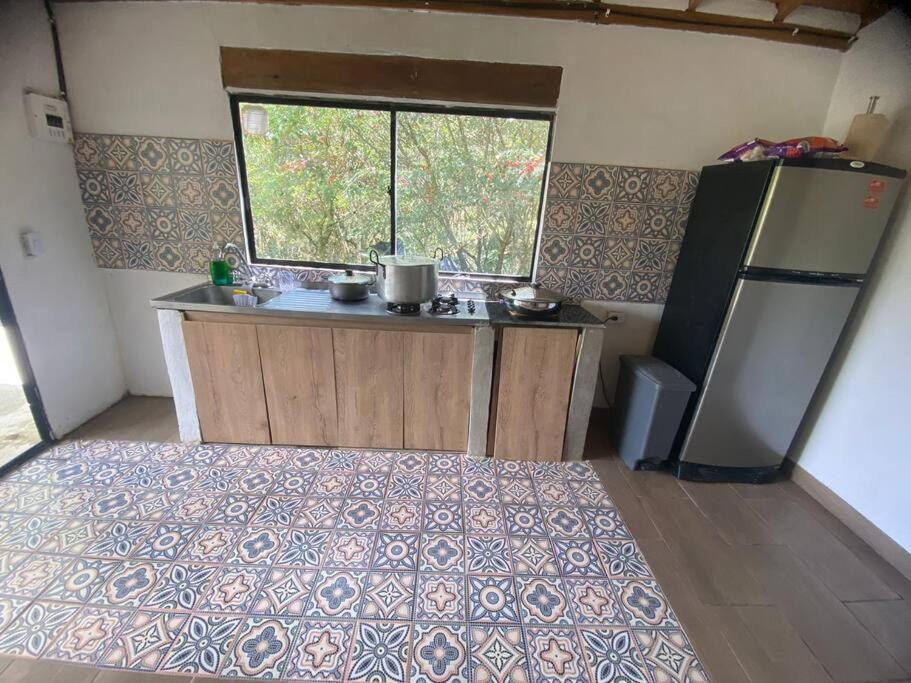 una pequeña cocina con nevera y ventana en Casa de campo El bosque de julia en Medellín