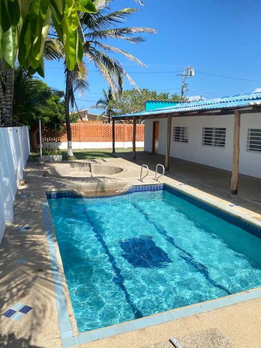 een zwembad met blauw water voor een huis bij Cabaña con piscina y Cerca al mar VILLA CONEJO in Juan de Acosta