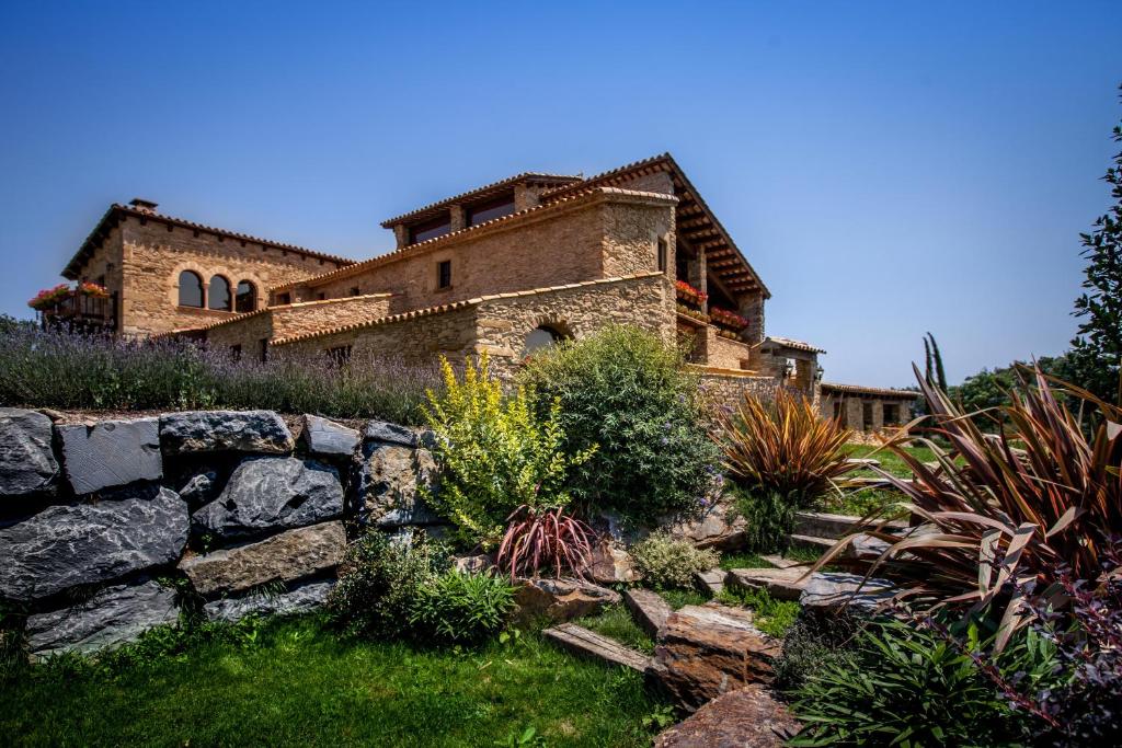 an old stone house with a stone wall in a garden at Estança La Pau - Adults Only in Malla