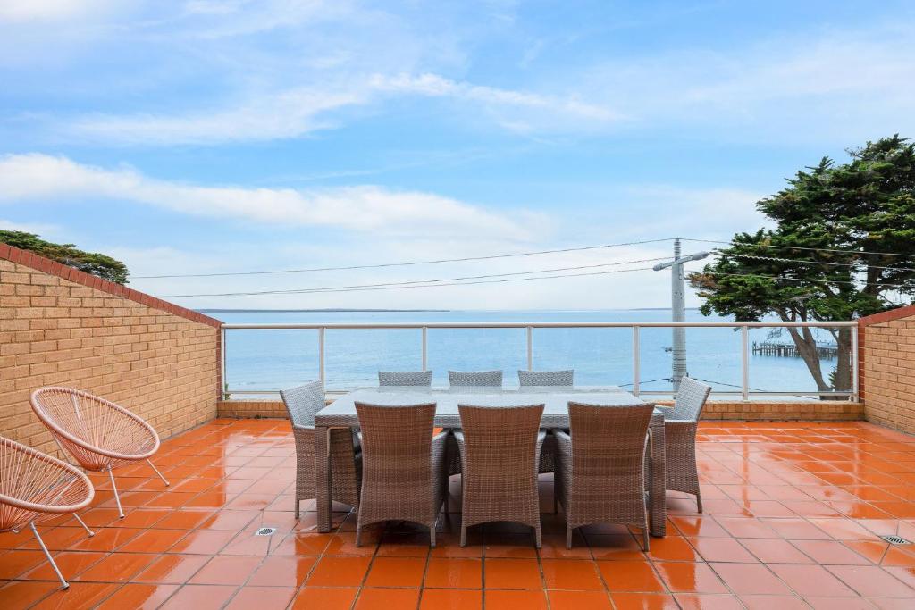a table and chairs on a balcony with the ocean at Beachfront Bliss - shared indoor pool & spa in Cowes