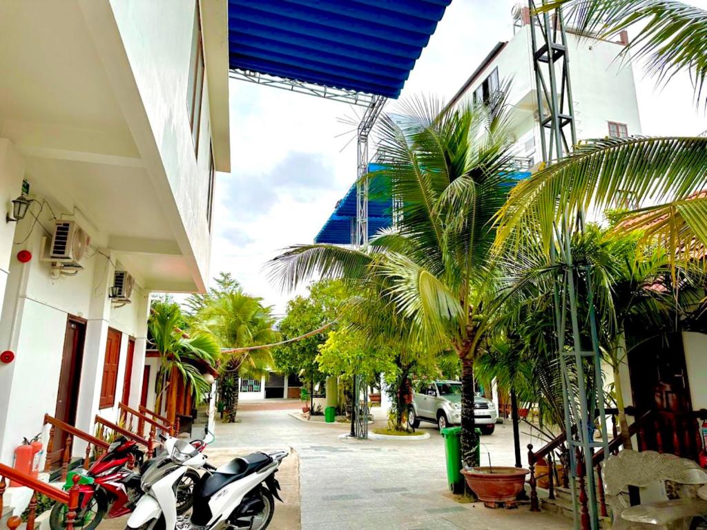 a motorcycle parked on a street with palm trees at Sân Vườn Hotel Khánh Hòa in Ninh Hòa