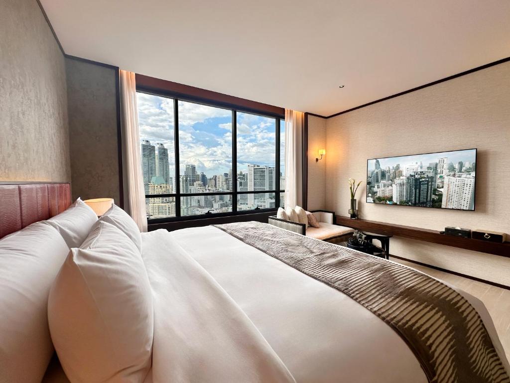 A suite bedroom with a king bed, lounge chair, and expansive skyline outlook.