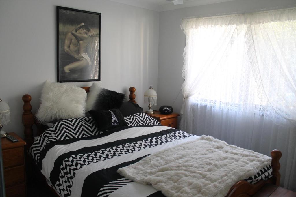 a bed with black and white blankets and a window at Ducati's B and B in Raymond Terrace