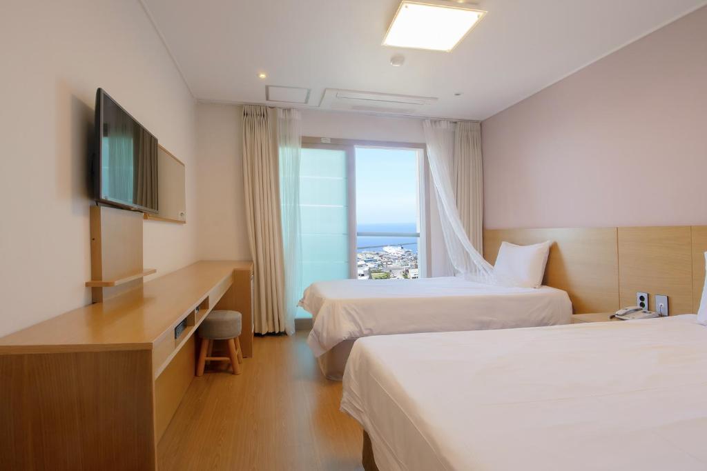 a hotel room with two beds and a television at Sims Hotel in Jeju