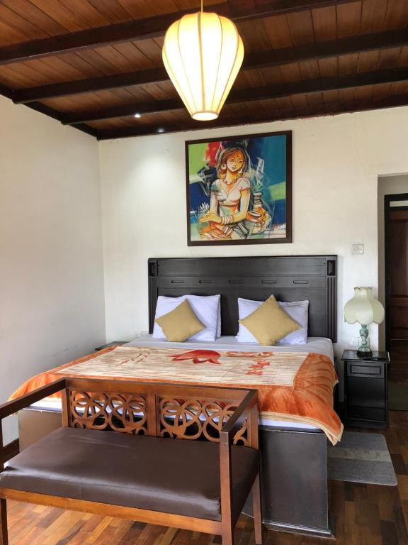 a bedroom with a large bed with a painting on the wall at Gregory's Bungalow in Nuwara Eliya