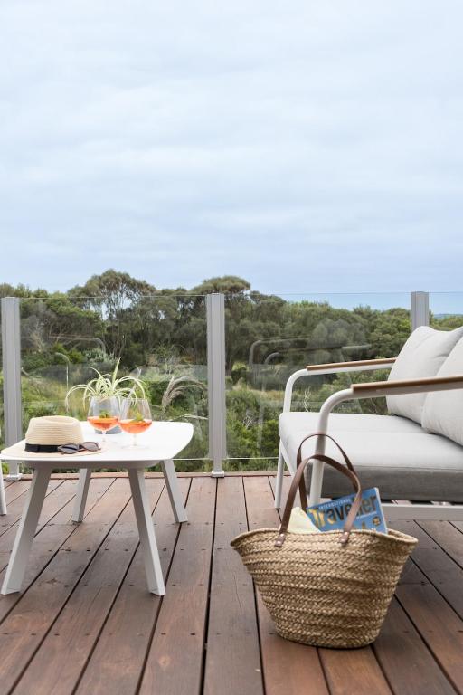 a patio with a table and a couch and a table at The Glasshouse in Saint Andrews Beach