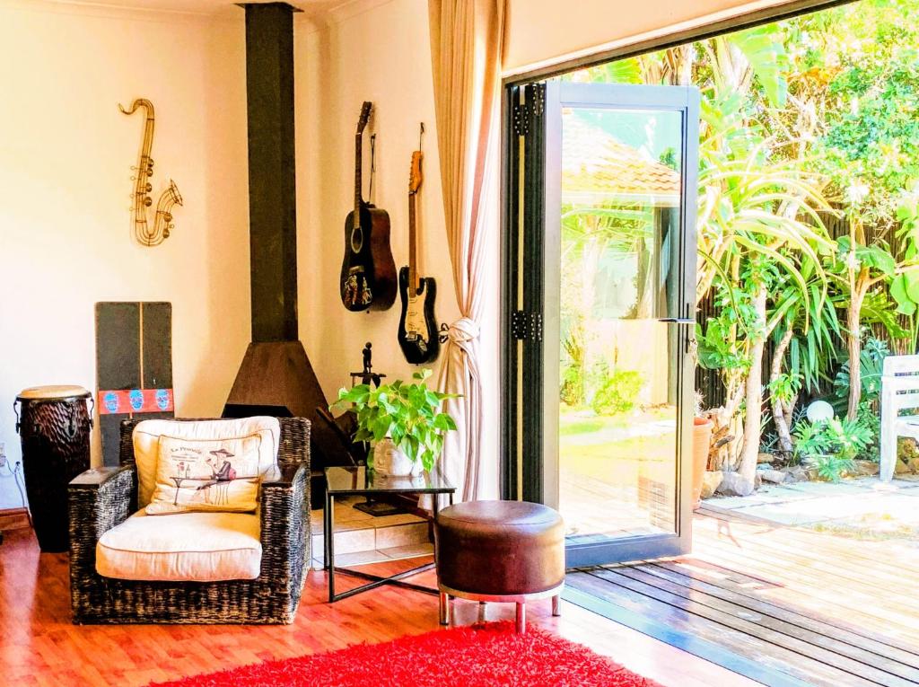 a living room with a chair and guitars on the wall at Spacious home in Cape Towns Blouberg area in Cape Town