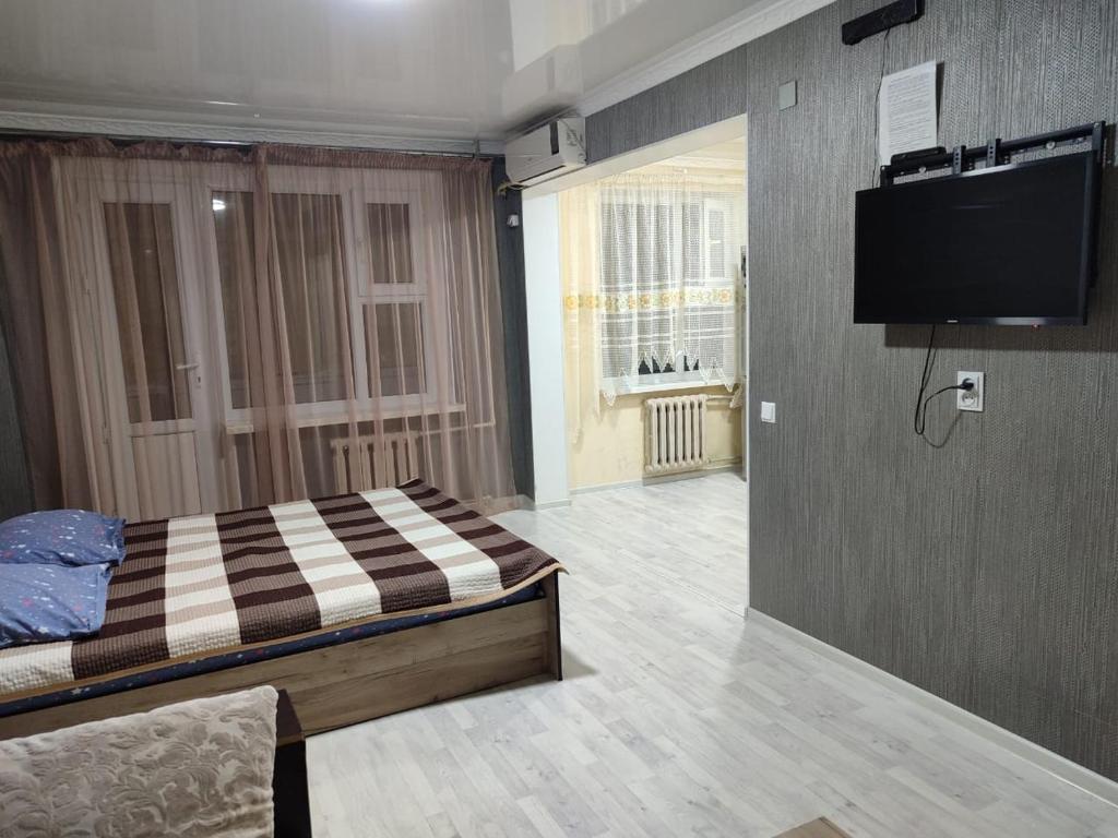 a bedroom with a bed and a flat screen tv at 1-комнатная квартира ЖК Акмечеть in Qyzylorda