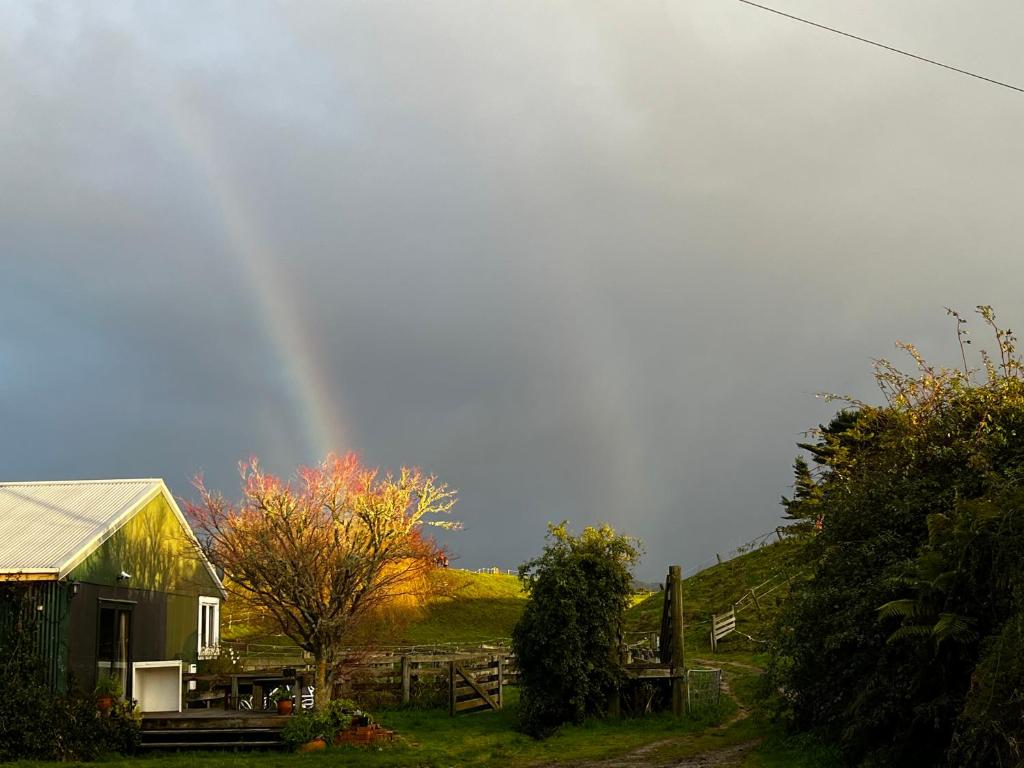 a rainbow in the sky over a house with a barn at Rainbow Mountain cottage in Rotorua