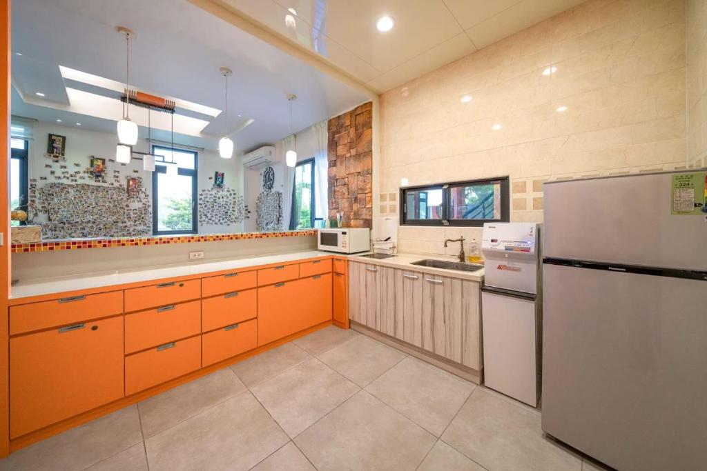 a large kitchen with orange cabinets and a refrigerator at Yilan My House Homestay B&amp;B in Dayin