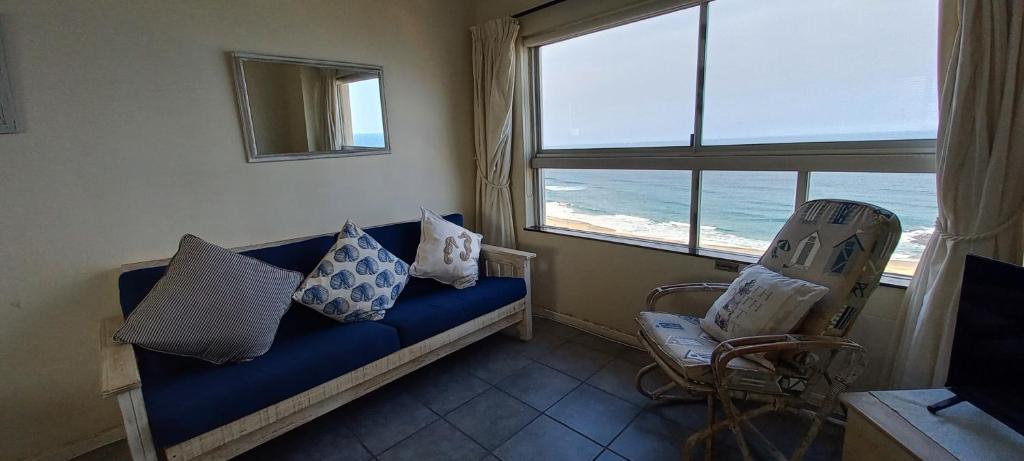 a living room with a blue couch and a view of the ocean at 703 High Tide, Holiday Apartment, Main Beach, Amanzimtoti in Amanzimtoti