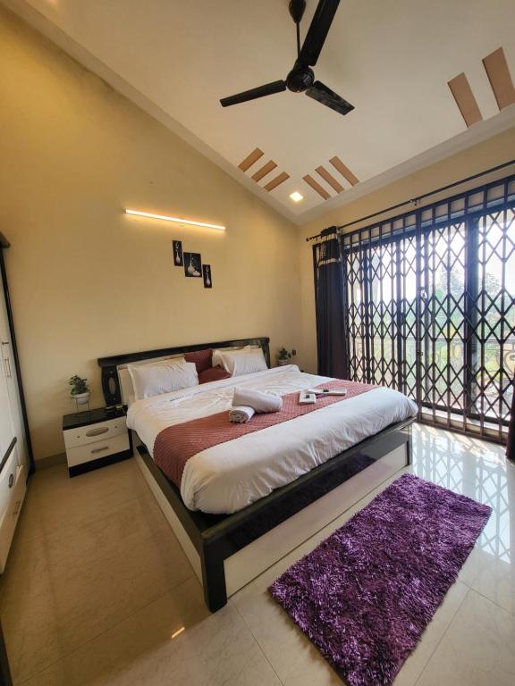 - une chambre avec un grand lit et un ventilateur de plafond dans l'établissement THE PERFECT STAYS: CHOUDHARY VILLA, à Lonavala