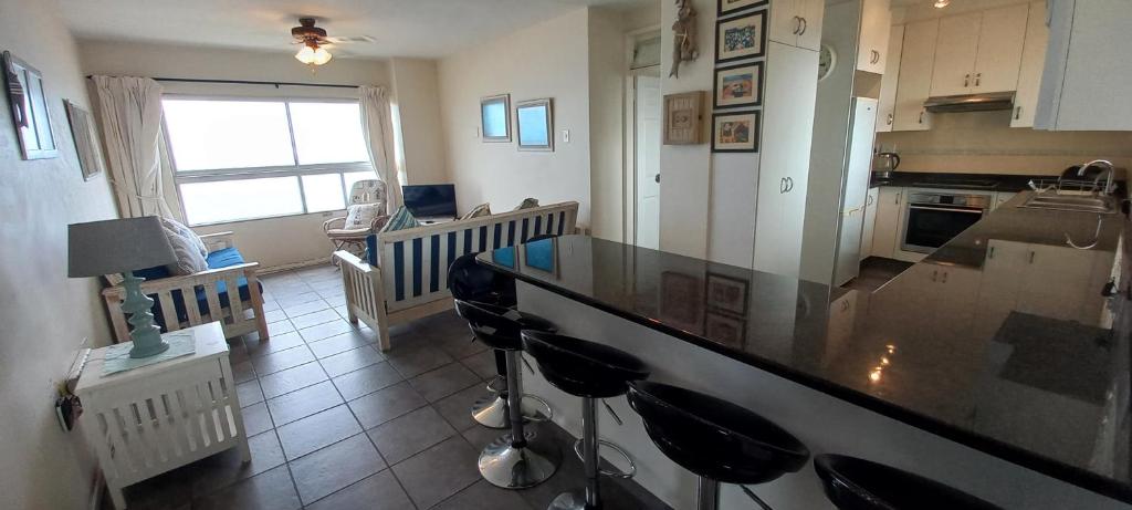 a kitchen with a counter with stools in it at 703 High Tide, Holiday Apartment, Main Beach, Amanzimtoti in Amanzimtoti