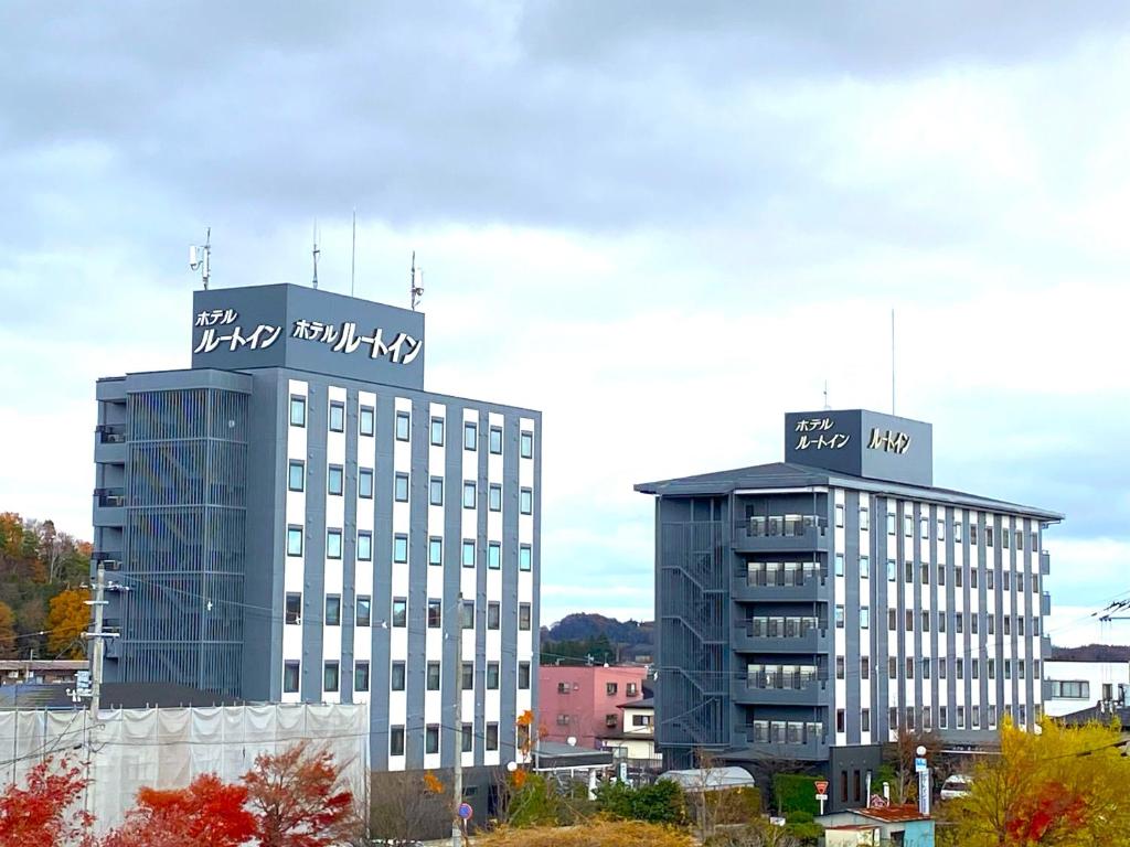 dos edificios altos con escritura encima de ellos en Hotel Route-Inn Shin-Shirakawa Eki Higashi en Shirakawa