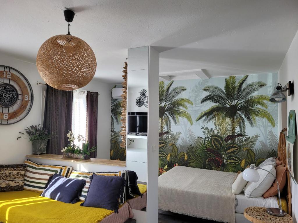 a bedroom with a bed and palm trees on the wall at Loft 40m2 avec terrasse pilotis in Fréjus