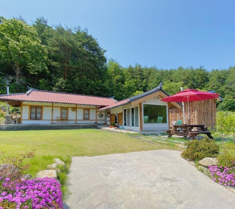 a house with a table and an umbrella in a yard at NK House in Gangneung