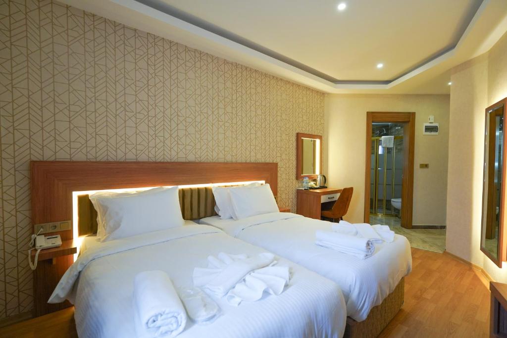Dos camas en una habitación de hotel con toallas. en Ugurlu Hotel en Gaziantep