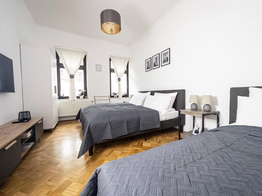 um quarto com 2 camas, uma mesa e 2 janelas em Erstklassige 3-Zimmer Wohnung em Leipzig