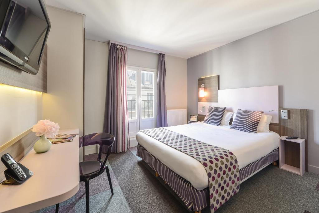 パリにあるHôtel de Charonneのベッドとデスクが備わるホテルルームです。