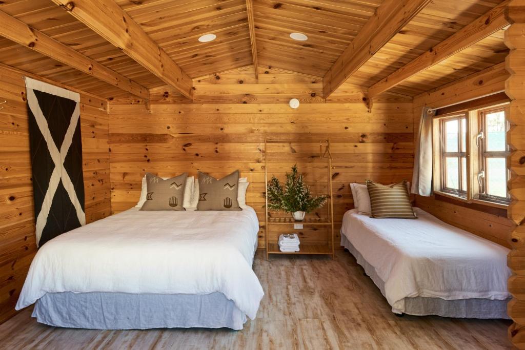 Tenterfield Lodge Caravan Park في تينتيرفيلد: سريرين في غرفة نوم كابينة خشب بجدران خشبية
