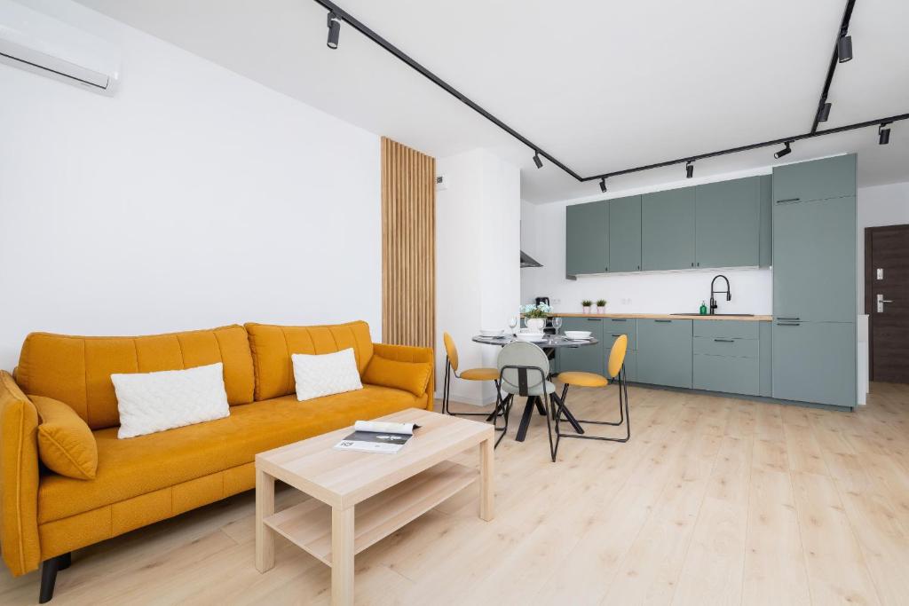 a living room with a yellow couch and a table at Stylish Apartment with Parking in Katowice by Renters in Katowice
