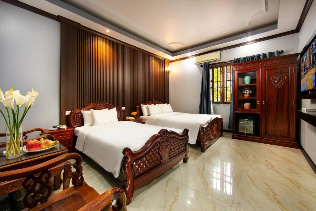 Un dormitorio con 2 camas y una mesa con un bol de fruta en Nam Hai Hotel en Hanói