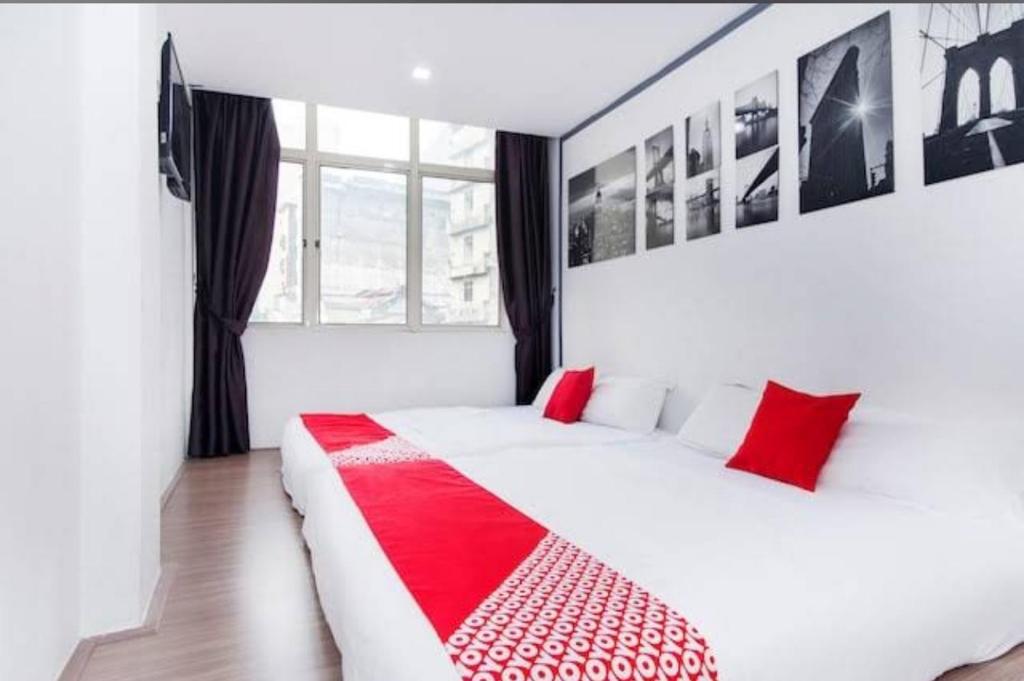 una camera da letto con un letto bianco con cuscini rossi di SAND HOTEL a Kuala Lumpur