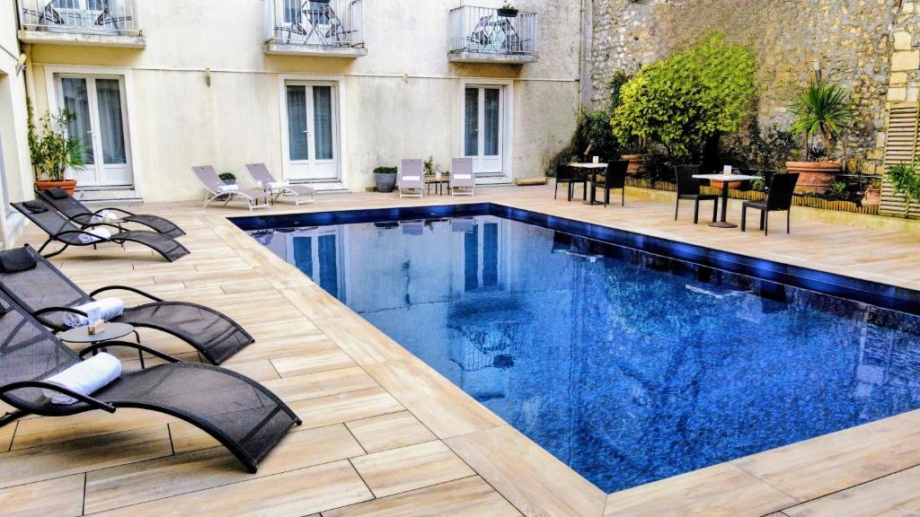 une grande piscine avec des chaises et une table dans l'établissement Hôtel Le Yachtman, The Originals Collection, à La Rochelle