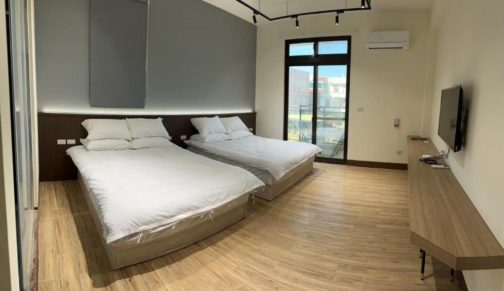 a bedroom with two beds and a flat screen tv at 五星佶民宿 in Jinning