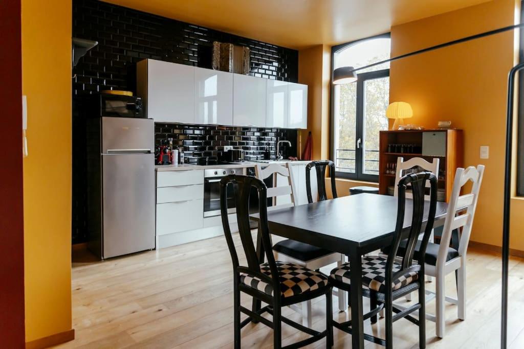 una cucina con tavolo nero ed elettrodomestici bianchi di Le rétro chic - Grand Duplex pour 6 dans le centre a Liegi
