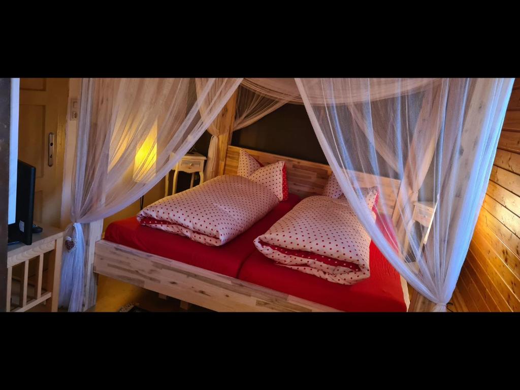 a bedroom with a red bed with mosquito nets at NEU! Ferienhaus am Klostergarten Gössweinstein in Gößweinstein