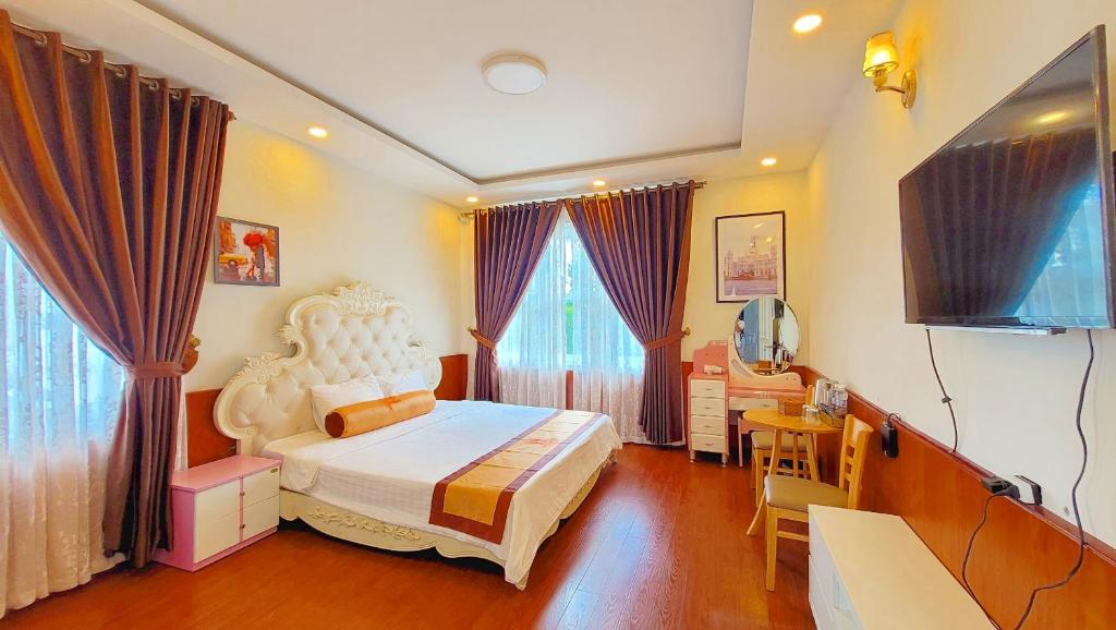 1 dormitorio con 1 cama y TV en Villa H Flower Đà Lạt en Da Lat