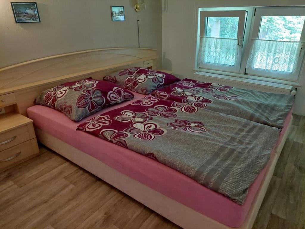 a bedroom with a bed with red and gray blankets and pillows at NEU! FeWo unter Reet am Wald auf Rügen in Lohme