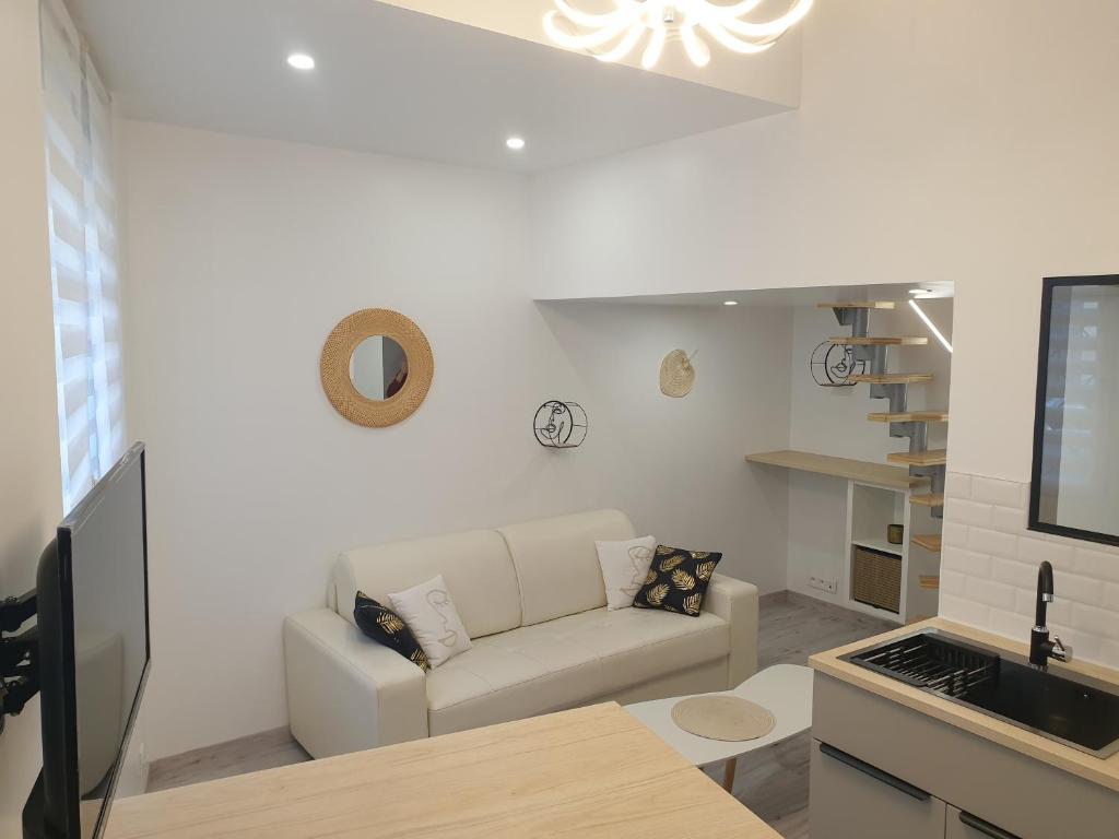 uma sala de estar branca com um sofá e uma cozinha em Mezza'Nîmes em Nîmes