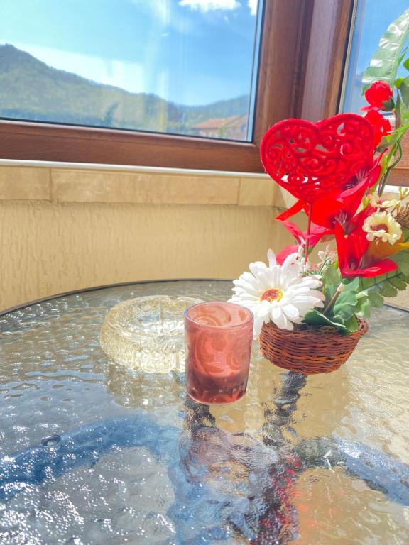 una mesa con un jarrón de flores y una vela en Апартамент за гости Байрактарова, en Smolyan