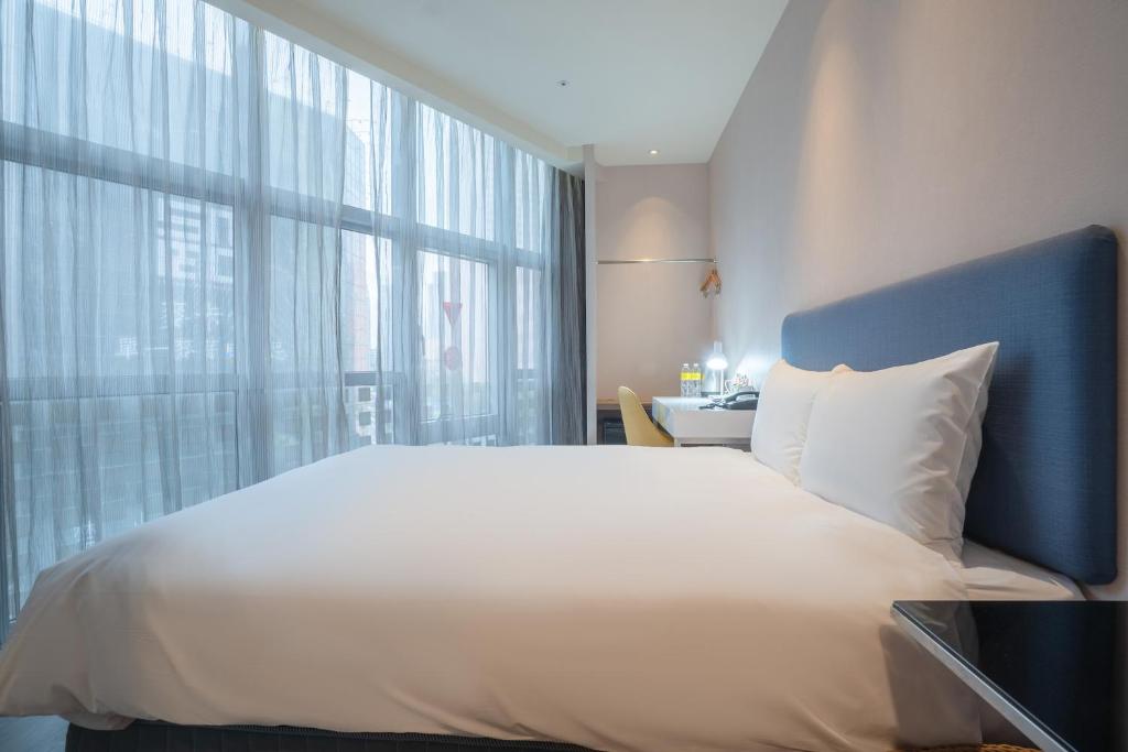 a bedroom with a large white bed and a window at CHECK inn Taipei Xinyi in Taipei