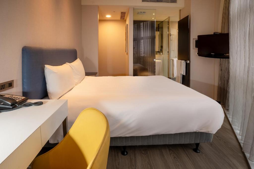 a bedroom with a large white bed and a yellow chair at CHECK inn Taipei Xinyi in Taipei