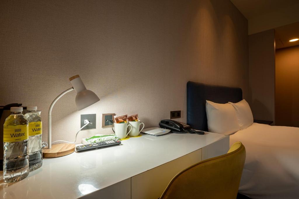 a room with a bed and a desk with a lamp at CHECK inn Taipei Xinyi in Taipei