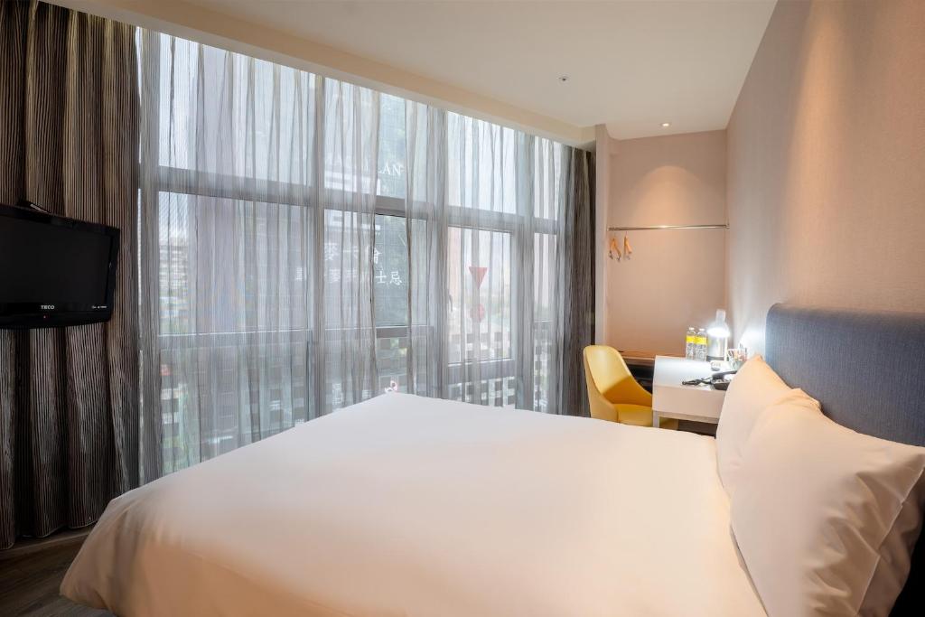 a bedroom with a white bed and a large window at CHECK inn Taipei Xinyi in Taipei
